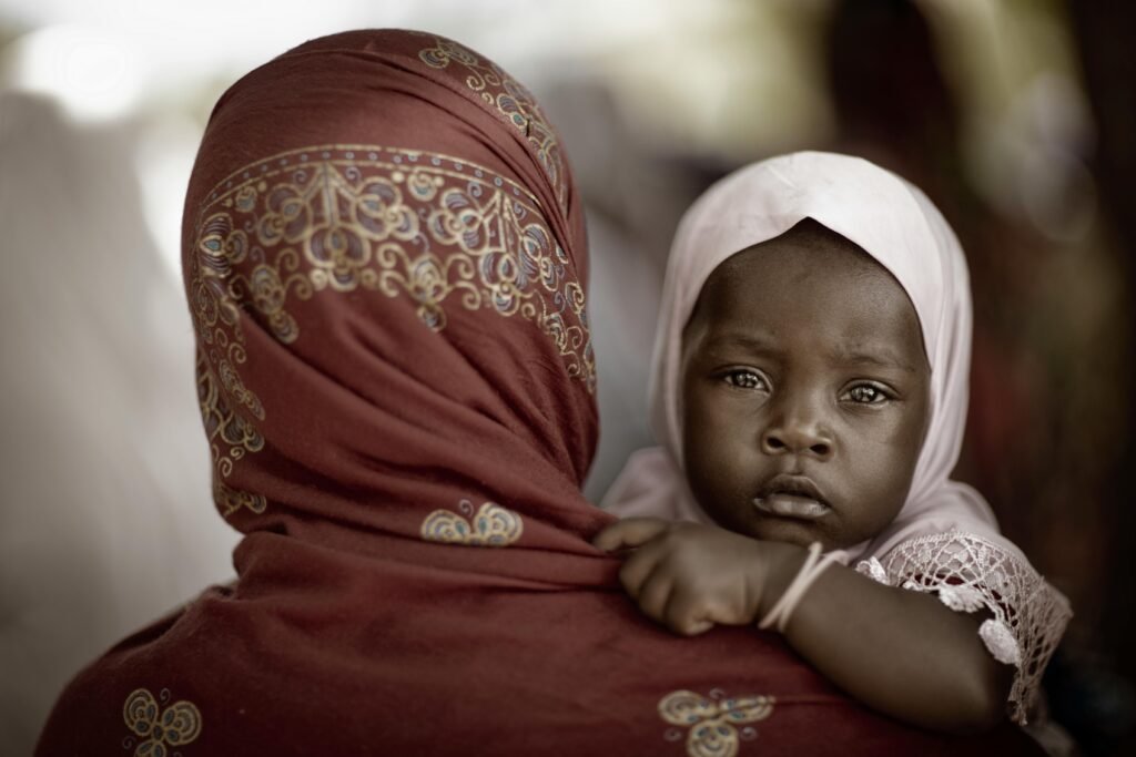 Mother in a Headscarf Carrying Her Little Daughter